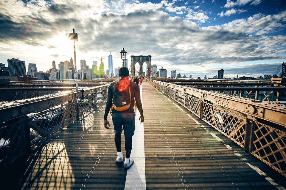 A person walking across a bridge into the city